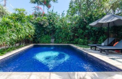 Impiana Private Villas Seminyak pool view. A gay-friendly hotel in Seminyak, Bali, with a private pool, lounge chairs, and lush tropical garden.