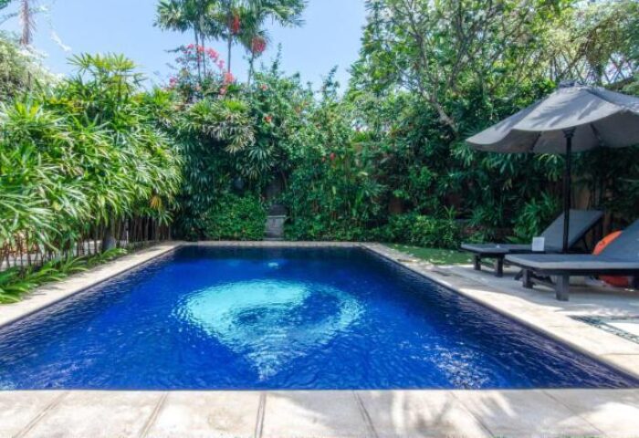Impiana Private Villas Seminyak pool view. A gay-friendly hotel in Seminyak, Bali, with a private pool, lounge chairs, and lush tropical garden.
