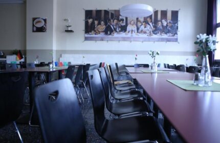 Industriepalast Hostel Berlin's dining hall. Long tables and chairs. The Last Supper parody art. Gay-friendly hotel, perfect for gay travelers.