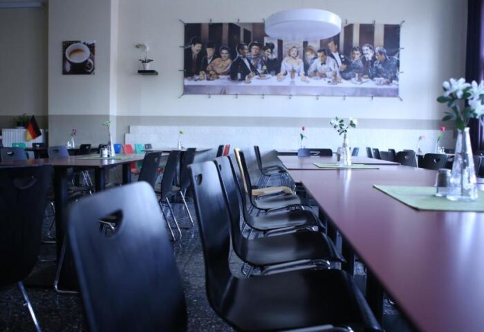 Industriepalast Hostel Berlin's dining hall. Long tables and chairs. The Last Supper parody art. Gay-friendly hotel, perfect for gay travelers.