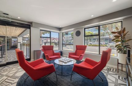 Infinity Hotel San Francisco lobby. Gay-friendly Tapestry Collection by Hilton. Red chairs surround a table. Modern interior design.