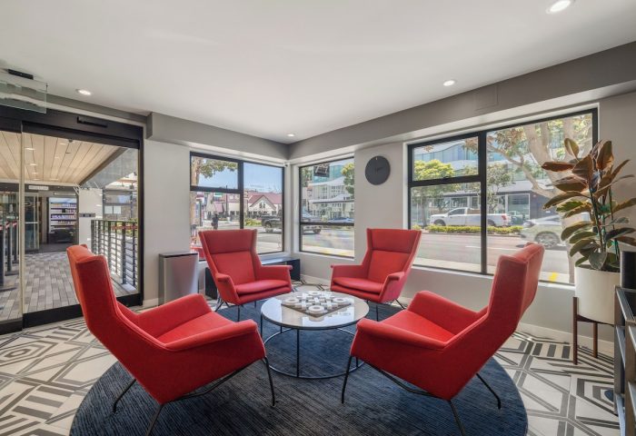 Infinity Hotel San Francisco lobby. Gay-friendly Tapestry Collection by Hilton. Red chairs surround a table. Modern interior design.