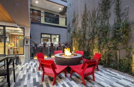 Infinity Hotel San Francisco courtyard with fire pit, red chairs, & ivy wall. Gay-friendly Tapestry Collection by Hilton hotel.