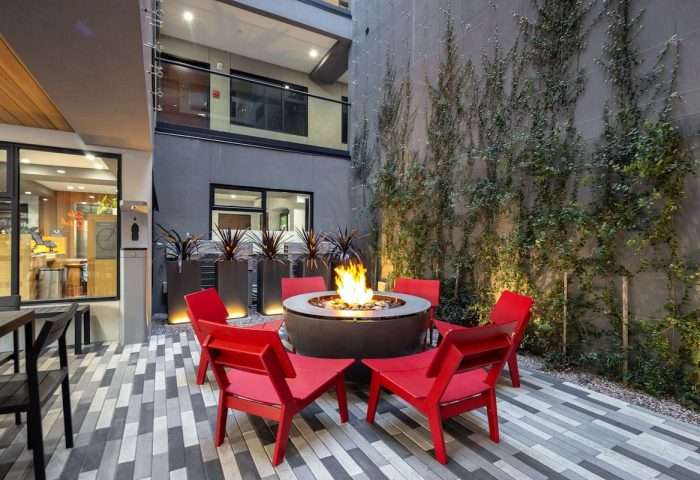 Infinity Hotel San Francisco courtyard with fire pit, red chairs, & ivy wall. Gay-friendly Tapestry Collection by Hilton hotel.