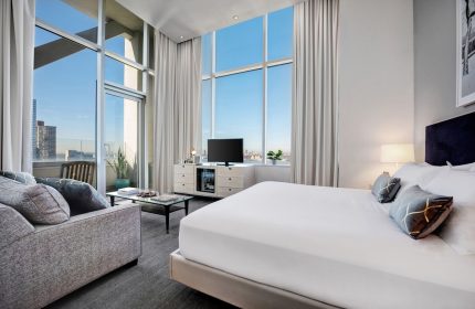 Ink 48 Hotel room. Gay-friendly hotel with city view, floor-to-ceiling windows, sofa, and king bed. Modern design for gay travelers.