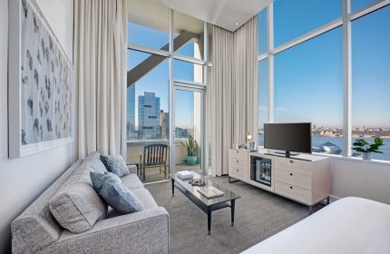 Ink 48 Hotel: Gay-friendly hotel room featuring a couch, TV, and a view of the city. Modern interior design, perfect for gay travelers.