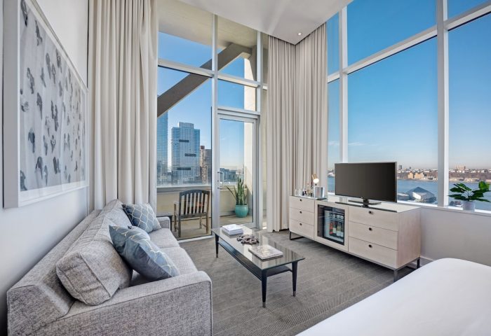 Ink 48 Hotel: Gay-friendly hotel room featuring a couch, TV, and a view of the city. Modern interior design, perfect for gay travelers.