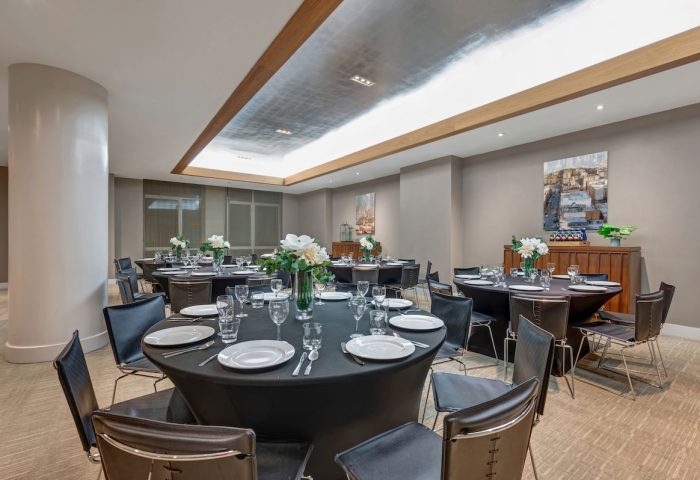Ink 48 Hotel's event space, a gay-friendly hotel, features round tables with black tablecloths, set for a sophisticated gathering.
