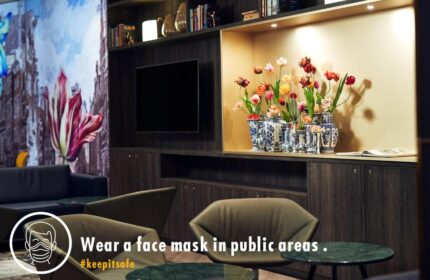 Inntel Hotels Amsterdam Centre lobby with tulips, TV, and seating. Gay-friendly, pet-friendly hotel. Wear a face mask in public areas. #keepitsafe