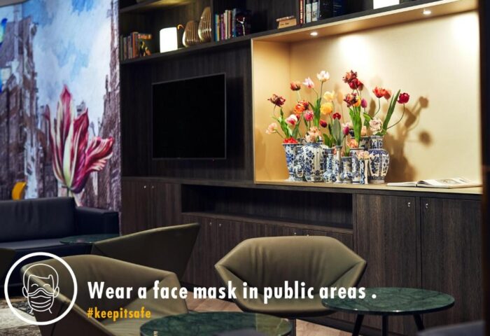 Inntel Hotels Amsterdam Centre lobby with tulips, TV, and seating. Gay-friendly, pet-friendly hotel. Wear a face mask in public areas. #keepitsafe