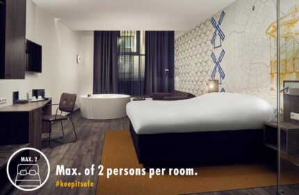 Gay-Friendly Inntel Hotels Amsterdam Centre room. Pet-friendly hotel room with jacuzzi, bed, desk, and Amsterdam themed wallpaper.