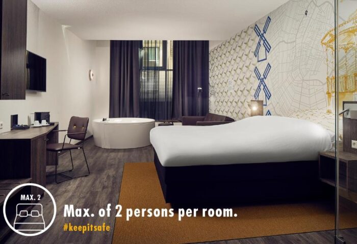 Gay-Friendly Inntel Hotels Amsterdam Centre room. Pet-friendly hotel room with jacuzzi, bed, desk, and Amsterdam themed wallpaper.