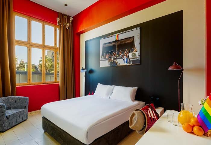 Room at Inta Hotel, Tel Aviv-Jaffa. Gay-friendly adults only hotel with a bed, desk, rainbow flag, and a photo of men on the wall.