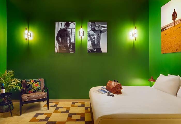 Inta Hotel, Tel Aviv-Jaffa. Gay-friendly adults-only room with green walls, male physique art, a bed, chair, and patterned tile floor.