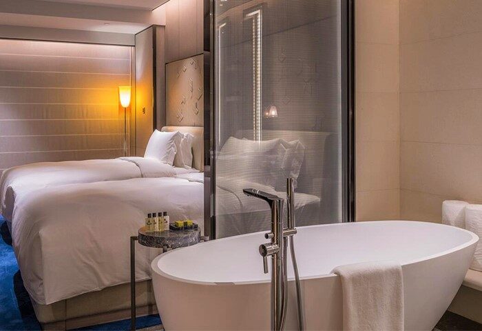 InterContinental Beijing Sanlitun gay-friendly hotel room. Modern bathtub in foreground, twin beds in background. Luxury travel for gay men.