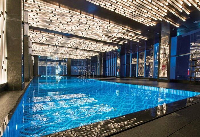 Indoor pool at the gay-friendly InterContinental Beijing Sanlitun hotel. Modern design with blue mosaic tiles and unique lighting.