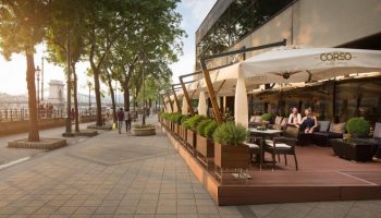 InterContinental Budapest gay-friendly hotel Corso terrace. Pet-friendly hotel with outdoor seating, a bridge, and people walking by.
