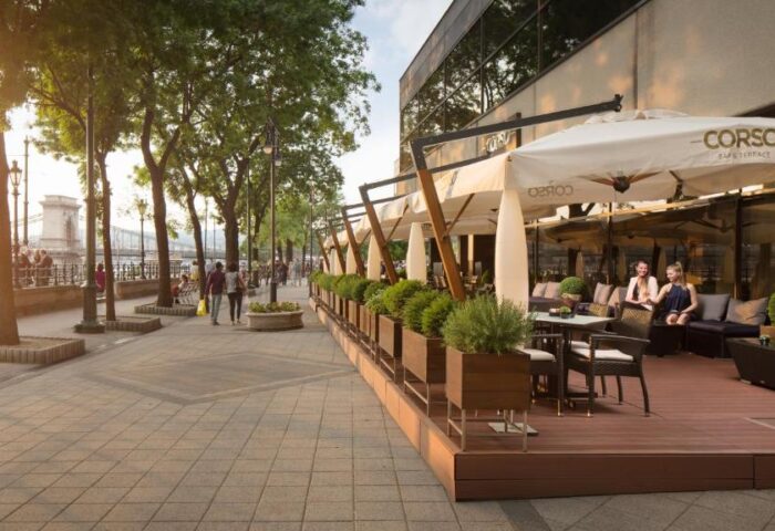 InterContinental Budapest gay-friendly hotel Corso terrace. Pet-friendly hotel with outdoor seating, a bridge, and people walking by.