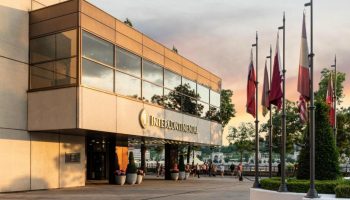 InterContinental Budapest, a gay-friendly, pet-friendly hotel. Facade view, flags, and Danube River background. Perfect for gay travel.