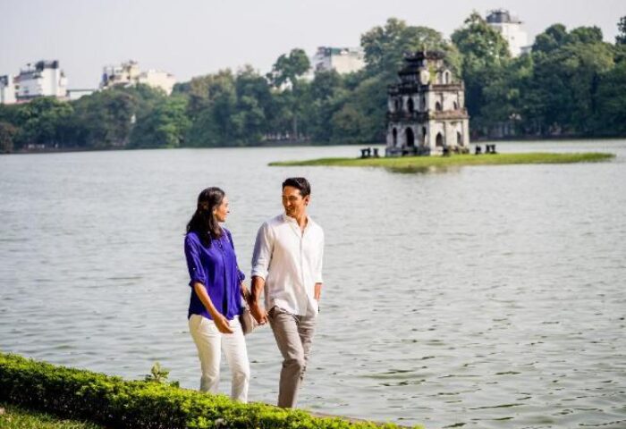 Gay-friendly InterContinental Hanoi Landmark72: Couple strolling by Hoan Kiem Lake, Hanoi. Turtle Tower is visible. Hanoi travel advice.