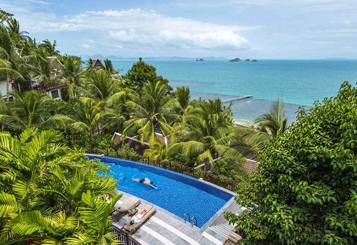 InterContinental Koh Samui Resort pool view. Gay-friendly hotel with ocean, palm trees, & pier. Perfect for gay men's travel in Thailand.
