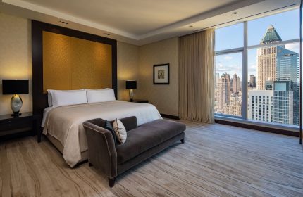 InterContinental New York Times Square gay-friendly hotel room. King bed, chaise lounge, city view. Luxurious gay travel accommodations.