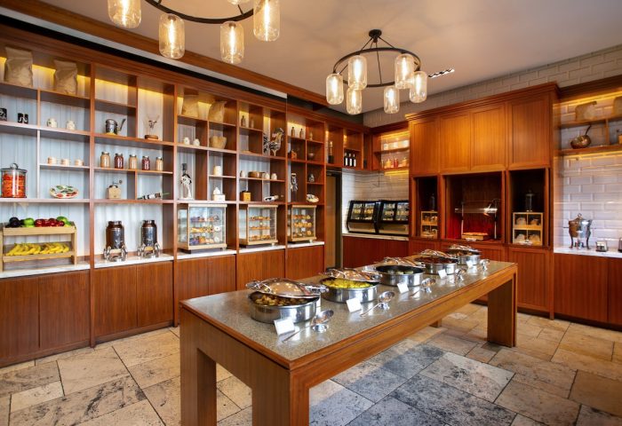 InterContinental New York Times Square gay-friendly hotel breakfast buffet. A long table with food warmers. Shelves with food items in the background.