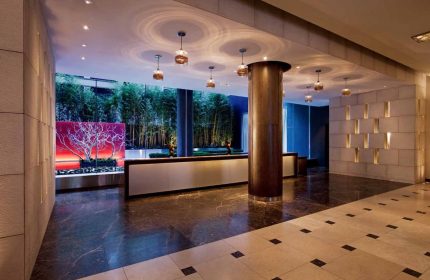 InterContinental New York Times Square lobby. Gay-friendly hotel interior with bamboo, modern lighting, and sleek reception desk. Upscale design.