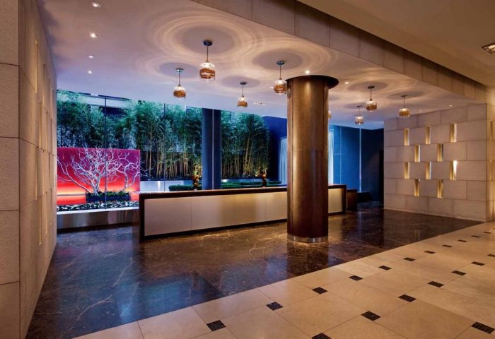 InterContinental New York Times Square lobby. Gay-friendly hotel interior with bamboo, modern lighting, and sleek reception desk. Upscale design.