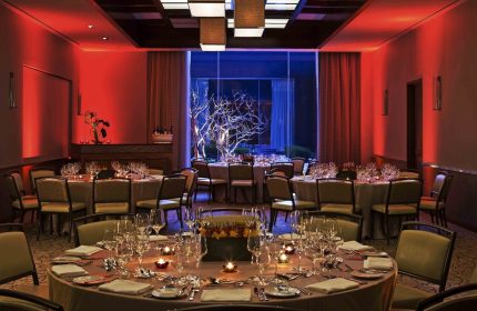 InterContinental New York Times Square gay-friendly hotel ballroom. Round tables set for a special event. Red and blue lighting.