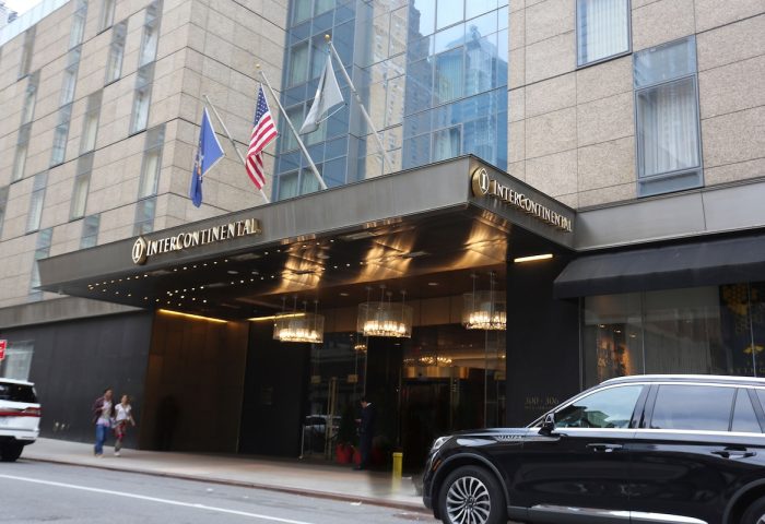 InterContinental New York Times Square, a gay-friendly hotel. Entrance view with flags, lighting, and a car parked nearby. Great for gay travel.