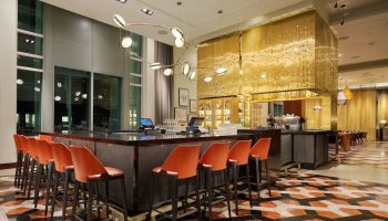 InterContinental San Francisco hotel bar. Modern design with orange chairs, patterned floor, and gold accents. A gay-friendly hotel choice.