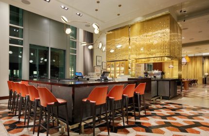 InterContinental San Francisco hotel bar. Modern design with orange chairs, patterned floor, and gold accents. A gay-friendly hotel choice.