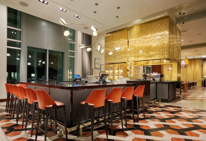 InterContinental San Francisco hotel bar. Modern design with orange chairs, patterned floor, and gold accents. A gay-friendly hotel choice.