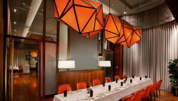 InterContinental San Francisco gay-friendly hotel dining room. Long table set for dinner, orange geometric light fixtures.