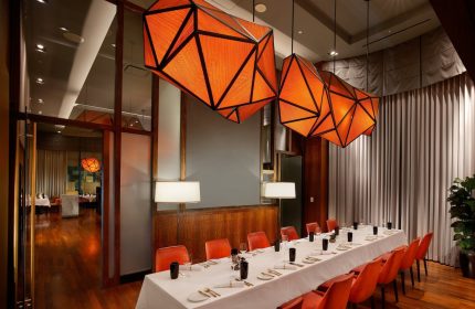 InterContinental San Francisco gay-friendly hotel dining room. Long table set for dinner, orange geometric light fixtures.