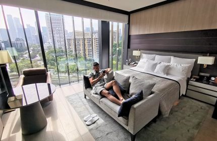 Gay-friendly InterContinental Singapore Robertson Quay hotel room. Man relaxing on sofa with city view. Luxury gay travel in Singapore.