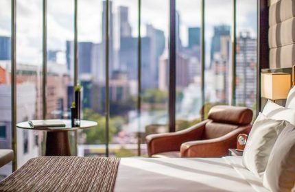 InterContinental Singapore Robertson Quay gay-friendly hotel room. City view from window, chair, and bed. Modern design.