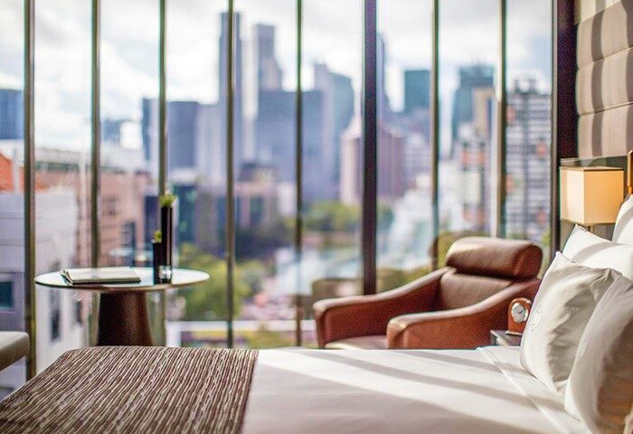 InterContinental Singapore Robertson Quay gay-friendly hotel room. City view from window, chair, and bed. Modern design.