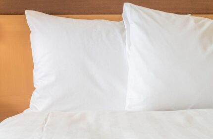 InterContinental Wien gay-friendly hotel bedroom. Crisp white pillows and duvet on a bed with a wooden headboard. Vienna travel advice.