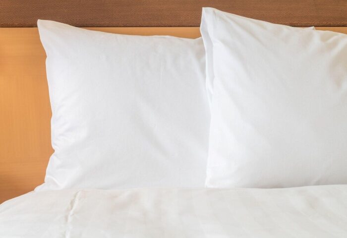 InterContinental Wien gay-friendly hotel bedroom. Crisp white pillows and duvet on a bed with a wooden headboard. Vienna travel advice.