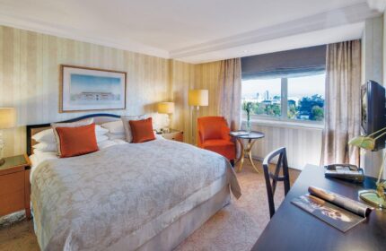 InterContinental Wien hotel room. Gay-friendly hotel bedroom with king bed, desk, chair, and city view. Vienna travel for gay men.