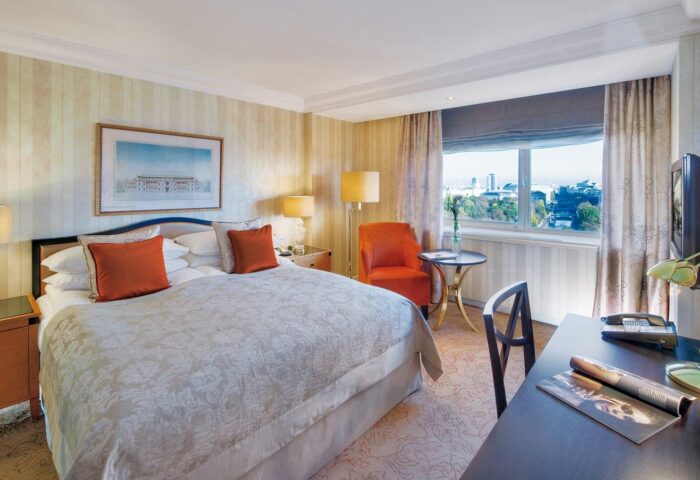 InterContinental Wien hotel room. Gay-friendly hotel bedroom with king bed, desk, chair, and city view. Vienna travel for gay men.