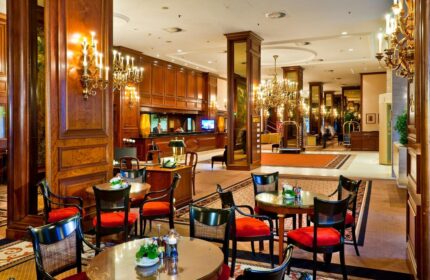 InterContinental Wien's lobby, a gay-friendly hotel. Elegant seating area with chandeliers and wood paneling. Ideal for gay men travelers.