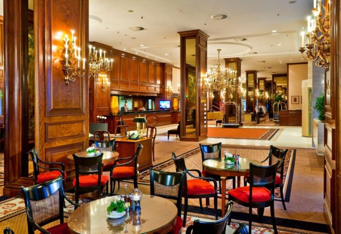 InterContinental Wien's lobby, a gay-friendly hotel. Elegant seating area with chandeliers and wood paneling. Ideal for gay men travelers.