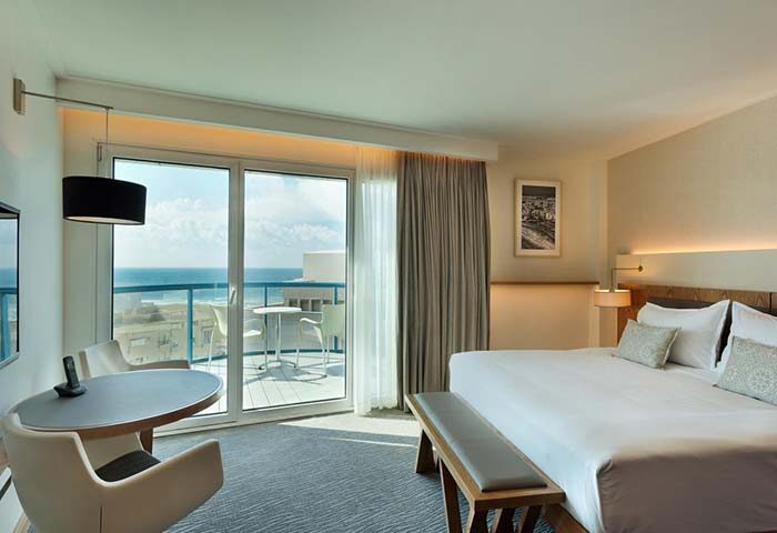 Isrotel Tower Hotel room with sea view. Gay-friendly hotel featuring a balcony, table, and king-size bed. A luxurious stay for gay travelers.