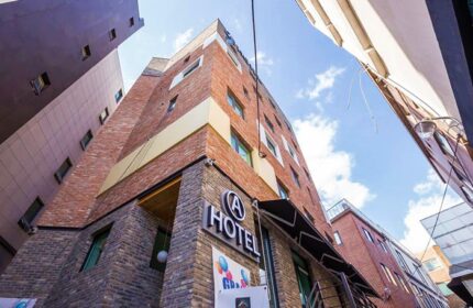 Exterior of Itaewon A One Hotel, a gay-friendly hotel in Seoul, South Korea. Brick building with A Hotel sign. Blue sky above.