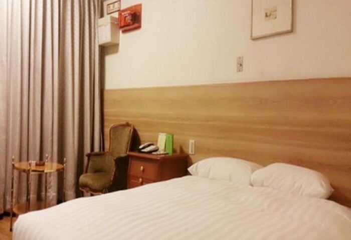 Itaewon Crown Hotel room. Gay-friendly hotel in Seoul, South Korea. Queen bed, chair, and nightstand. Comfortable lodging for gay travelers.