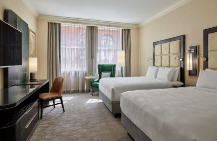 JW Marriott Chicago gay-friendly hotel room. Two beds with white linens, desk, chair, and window. Luxury accommodations in Chicago.