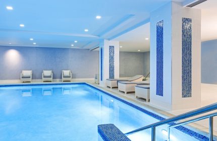 Indoor pool at the gay-friendly JW Marriott Chicago hotel. Relaxing space with lounge chairs, blue accents, and bright lighting.